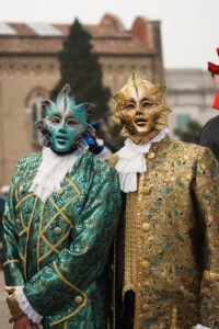 Protrait of 2 men dressed-up for venice carnival, one is wearing an emerald green suit and the other a golden suit. Ratio 2to3