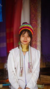 Portrait of a Kayan woman wearing traditional brass neck rings and a colorful embroidered headpiece