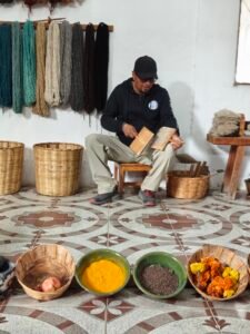 A artisan artisan sitting on the floor in a workshop, crafting mexican wool