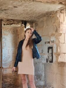 A woman posing inside the rustic stone interior of an ancient historical building.